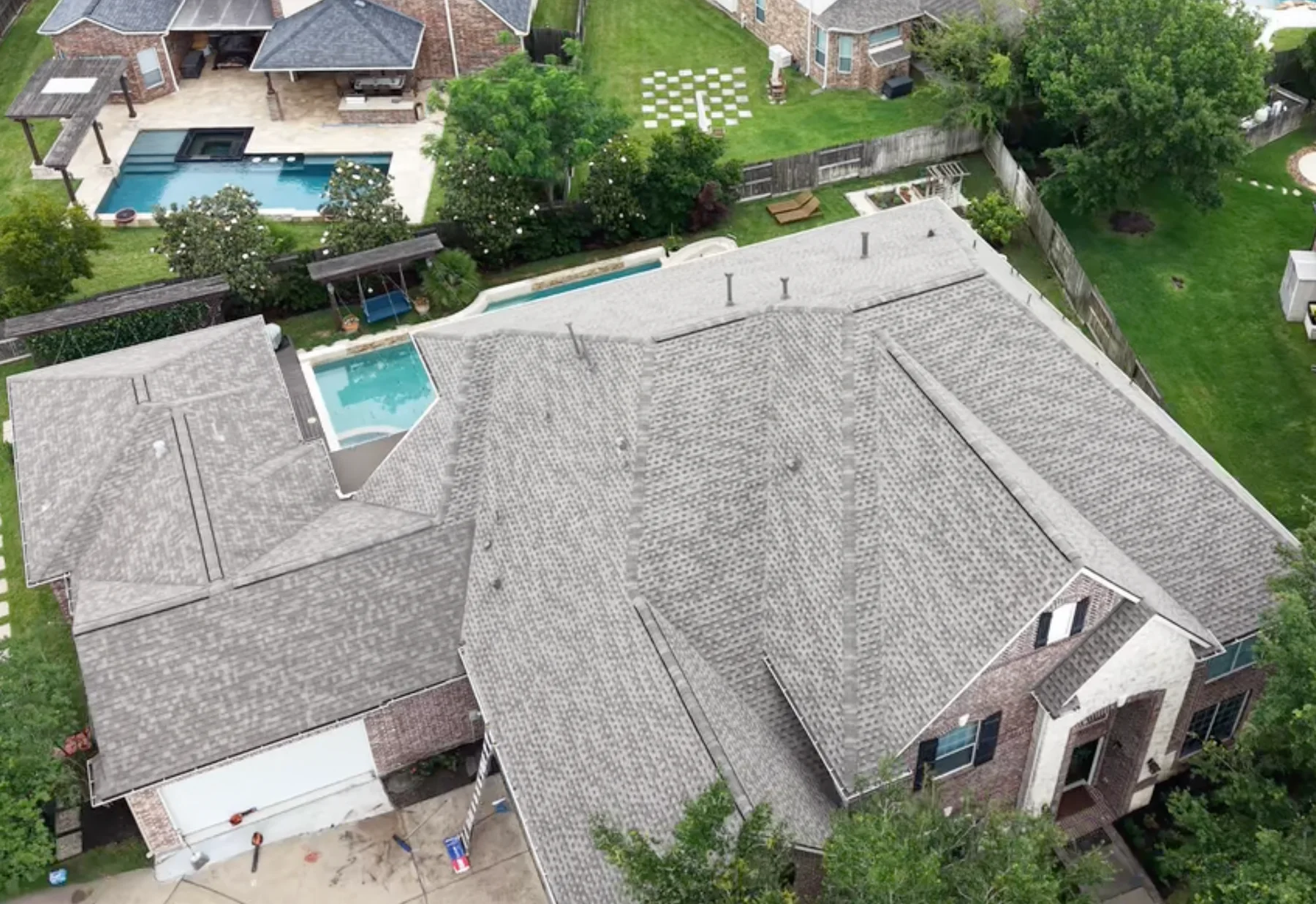 Wide aerial view of a gray shingle roof on a brick home.