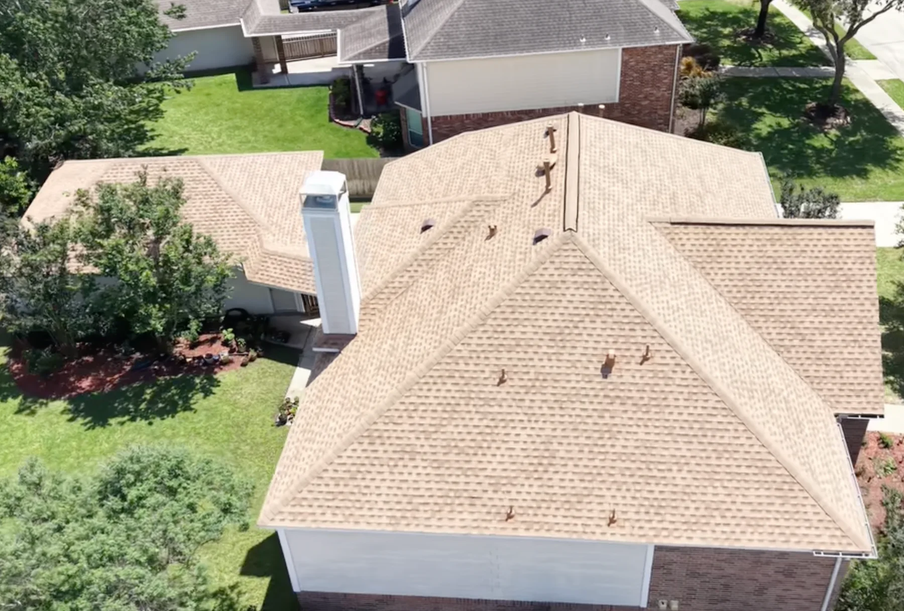 Aerial rear view of a light brown shingle roof with a chimney.