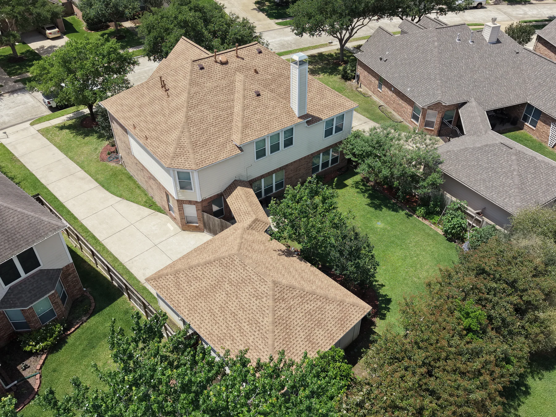 High aerial view of a light brown shingle roof in a residential neighborhood.