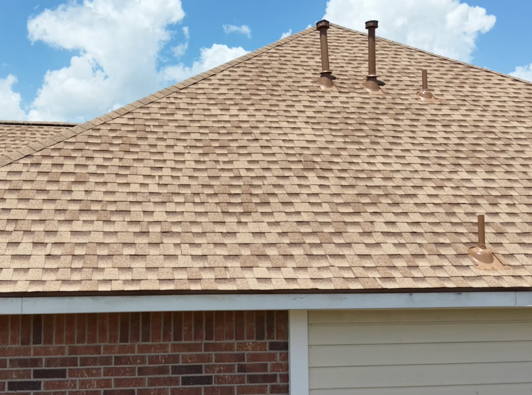 Light brown shingle roof with white drip edge above a garage.